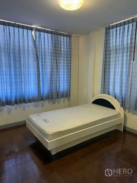 独立式住宅 出租在Bang Kapi, Bangkok - 次卧配单人床、蓝色窗帘与木地板。