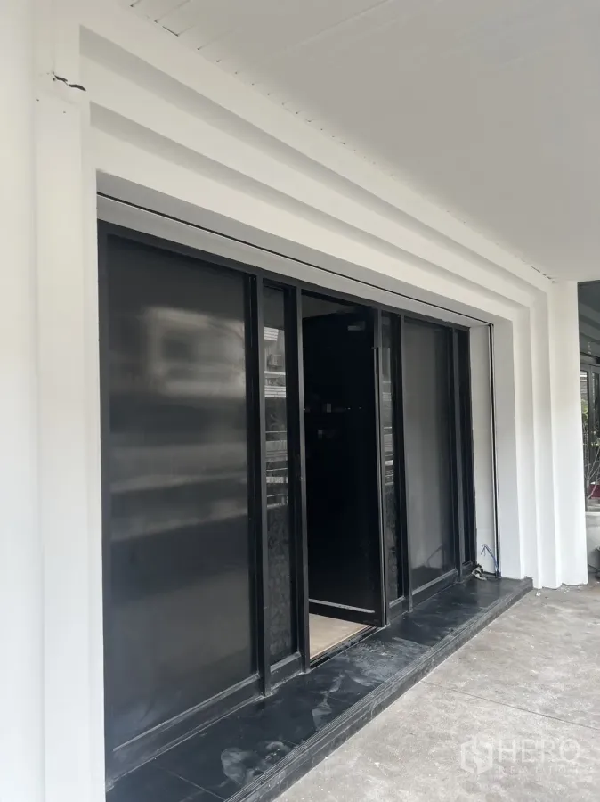 Retail Space for rent in Khlong Toei, Bangkok - Ground-floor retail storefront with black glass sliding doors and a white facade.