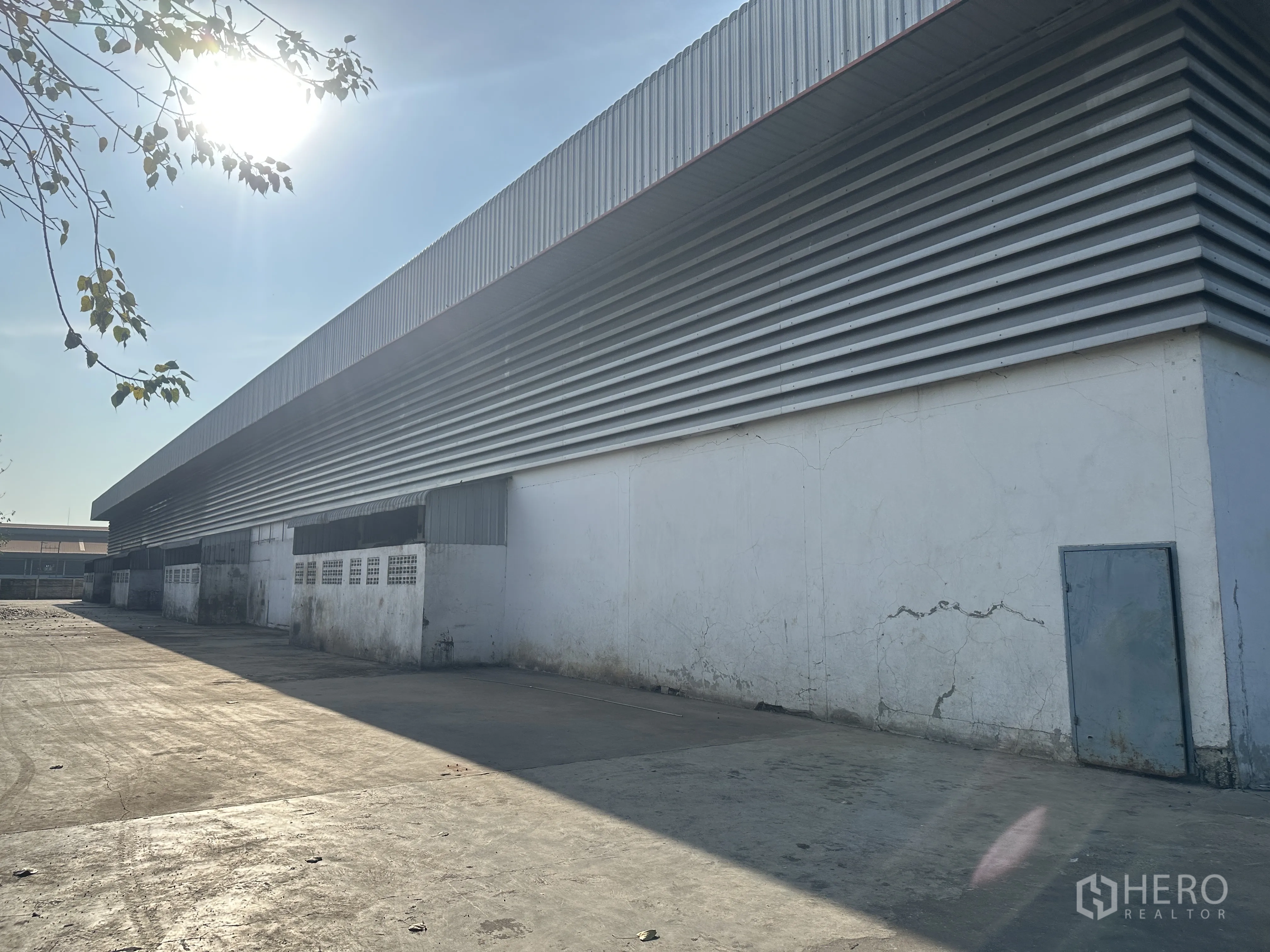 Factory for rent in Wang Noi, Phra Nakhon Si Ayutthaya - Exterior service lane beside the warehouse with metal louver panels and concrete paving.