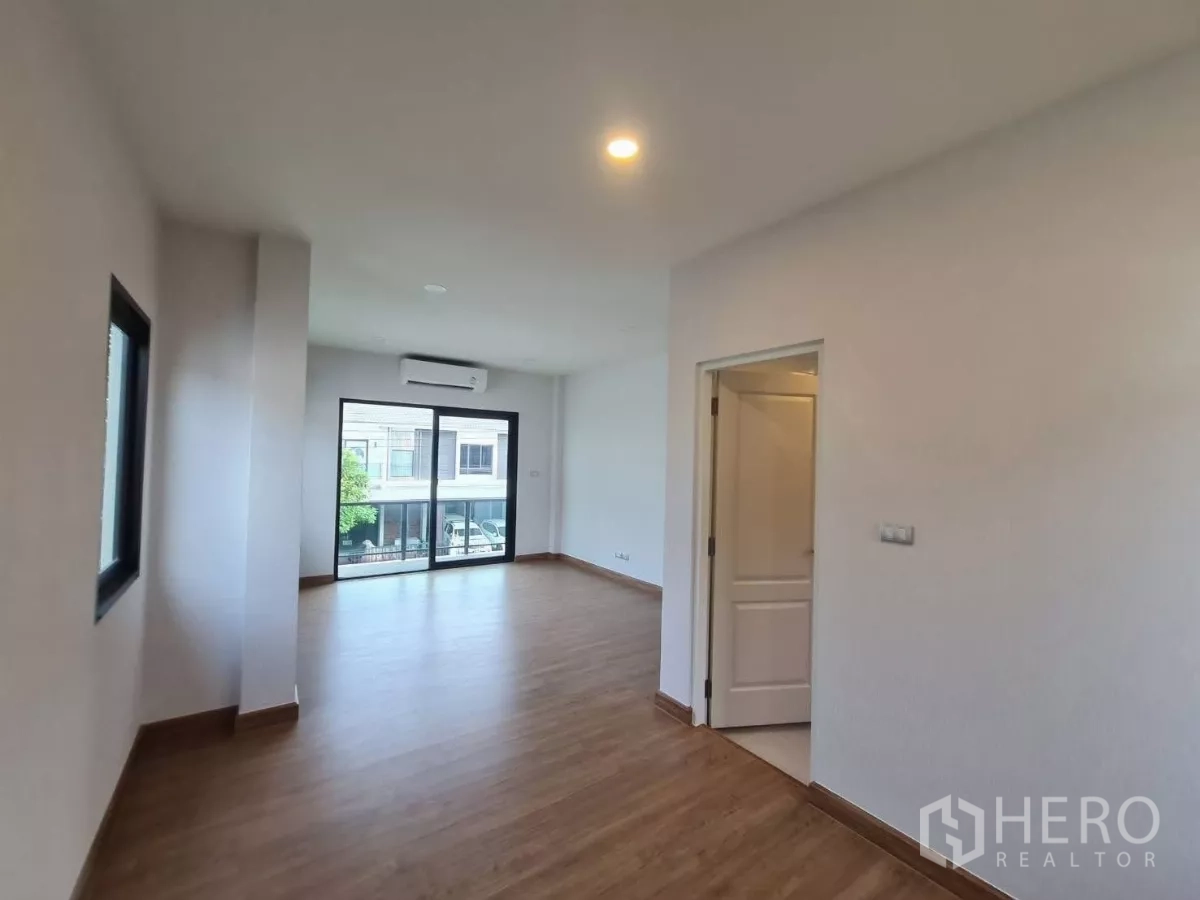 独立式住宅 出售在Samut Prakan - 二层房间带推拉门通阳台，装有空调并有相邻房门。