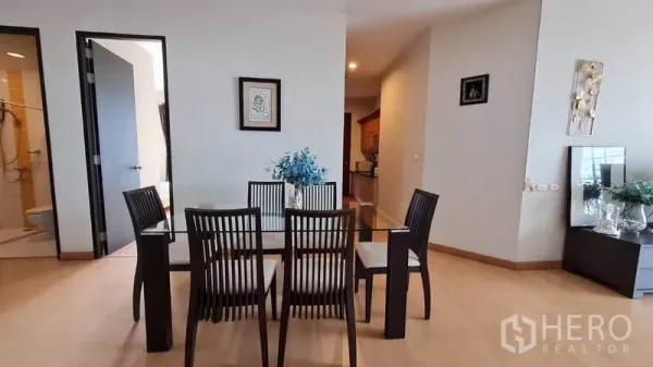 公寓 出租在Khlong Toei, Bangkok - 餐区配玻璃餐桌和六把椅子，旁连走廊与浴室入口