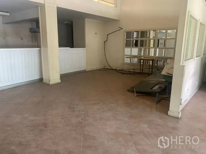Shophouse for rent in Watthana, Bangkok - Open-plan ground floor with tiled floor, mirror wall and a service counter.
