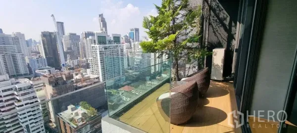 คอนโด ขายในWatthana, Bangkok - ระเบียงชั้นสูงพร้อมเก้าอี้หวาย ราวกระจก และวิวสกายไลน์กรุงเทพฯ แบบพาโนรามา