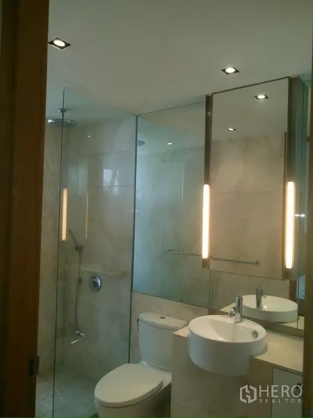 Condominium for rent in Sathon, Bangkok - Contemporary bathroom with glass shower, large mirror and vanity sink.