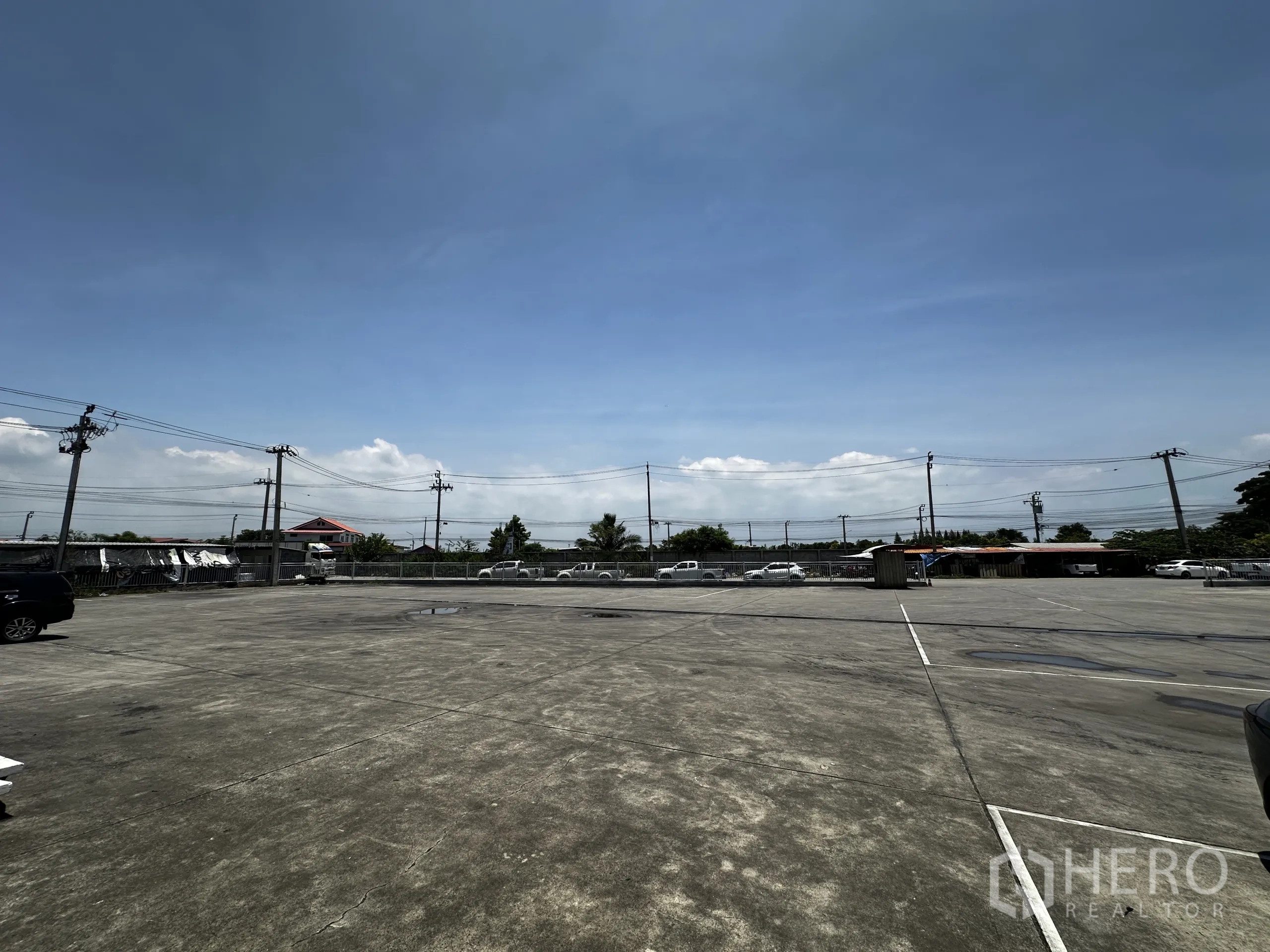 Warehouse for rent - Expansive outdoor parking and staging yard with perimeter fence and power lines.