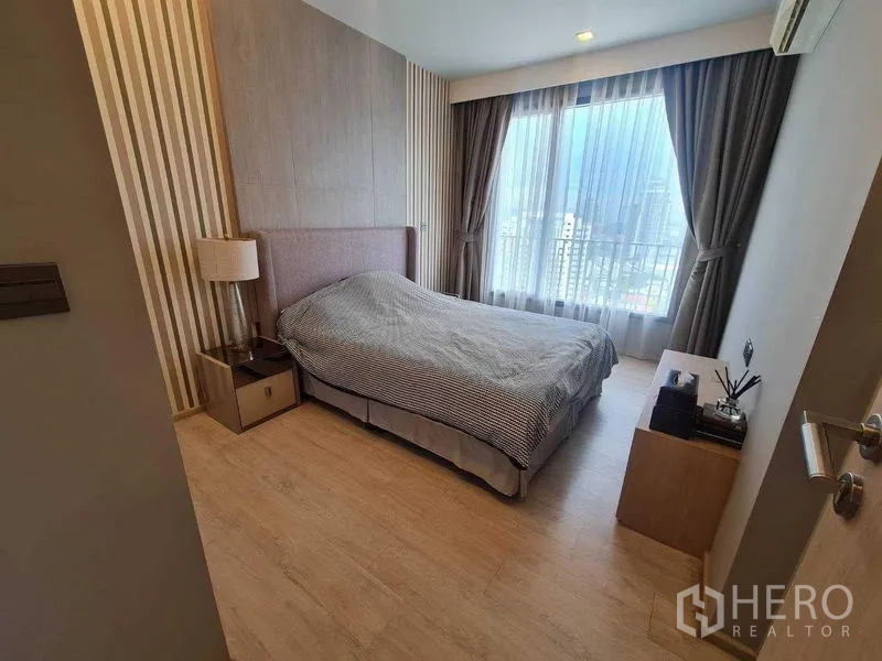 Condominium for sale - Cozy bedroom with striped feature wall, bedside tables and a full-height window.