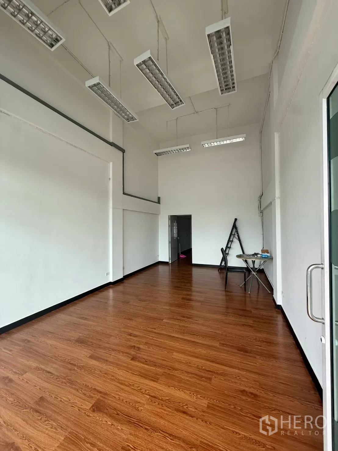 Shophouse for rent in Pak Kret, Nonthaburi - Wide view of the shop area with hanging strip lights and wood floor.