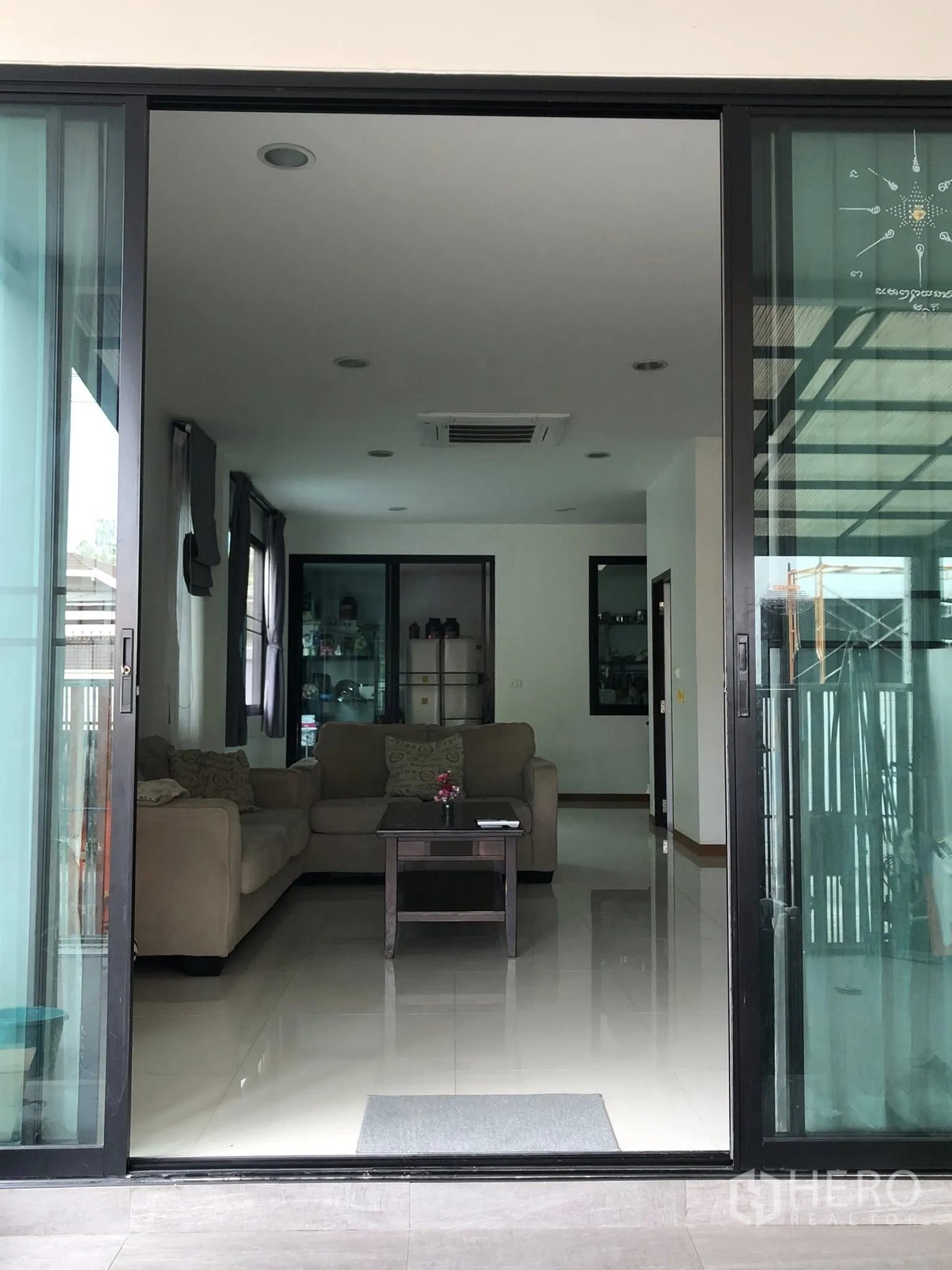 Townhouse for sale in Phra Khanong, Bangkok - Sliding doors opening to a bright living area with sofas and display cabinets.