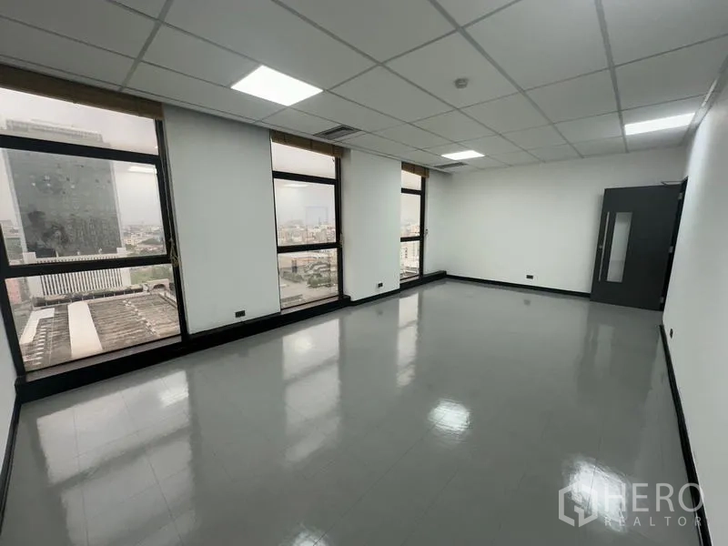 Office Space for rent - Large open office with big windows and city view under a drop ceiling.
