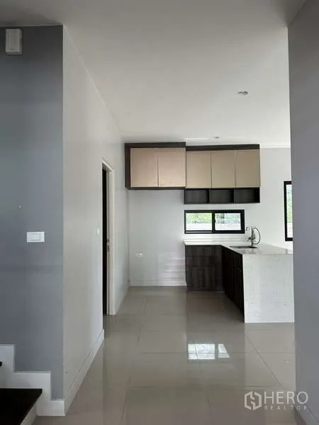 Detached House for sale in Lam Luk Ka, Pathum Thani - Built-in pantry cabinets with a central island in a light-tone kitchen.