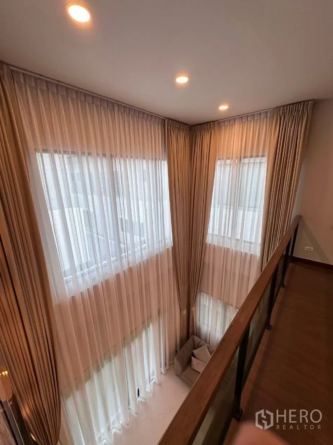 独立式住宅 出租在Bang Phli, Samut Prakan - 夹层走廊，玻璃栏杆俯瞰挑高客厅。