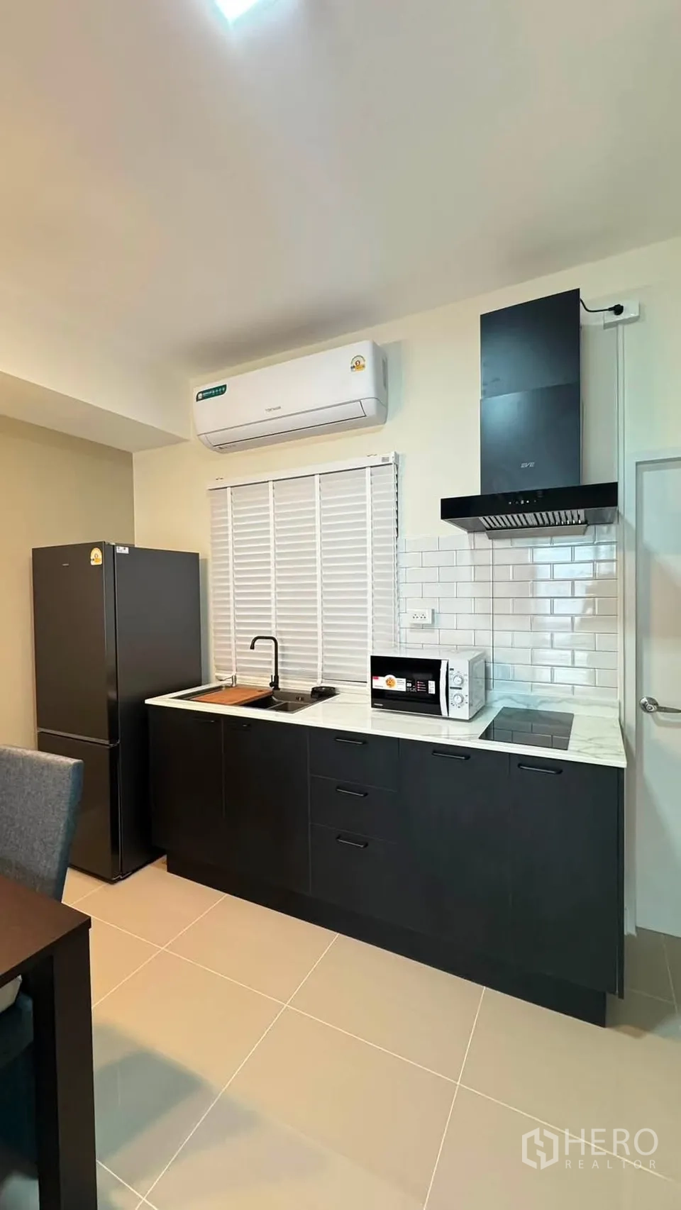 联排别墅 for rent in Bang Phli, Samut Prakan - 一字型厨房，黑色橱柜与大理石台面，配冰箱、微波炉、灶台与油烟机。