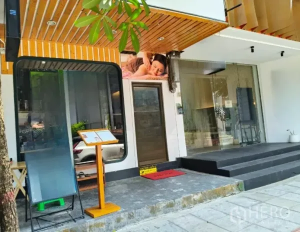 Shophouse for rent in Watthana, Bangkok - Street-level shophouse facade with wide glass entrance, wood soffit and steps in Watthana.