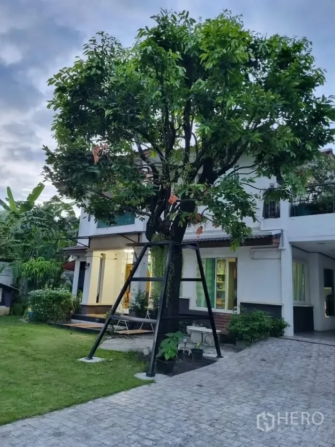 独立式住宅 出租在Bang Kapi, Bangkok - 两层独栋别墅，夕色下的大树、草坪与点灯门廊