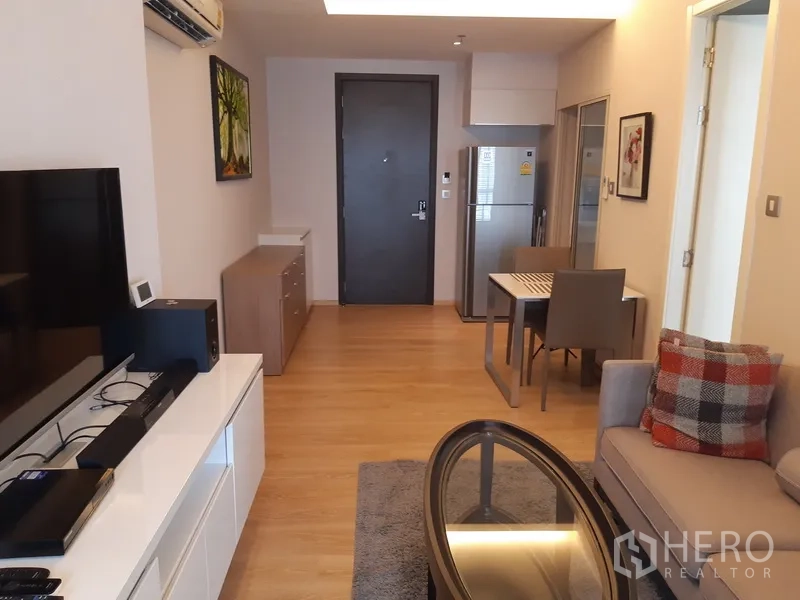 公寓 出租在Watthana, Bangkok - 从客厅望向入户门，餐桌与配有冰箱的现代厨房。