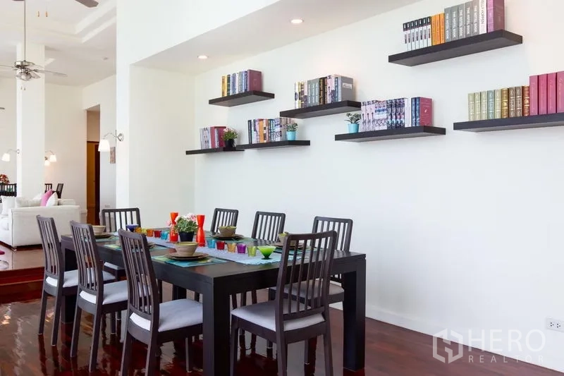 Condominium for rent in Bang Rak, Bangkok - Dining area with six-seat table and floating wall bookshelves on a white feature wall.