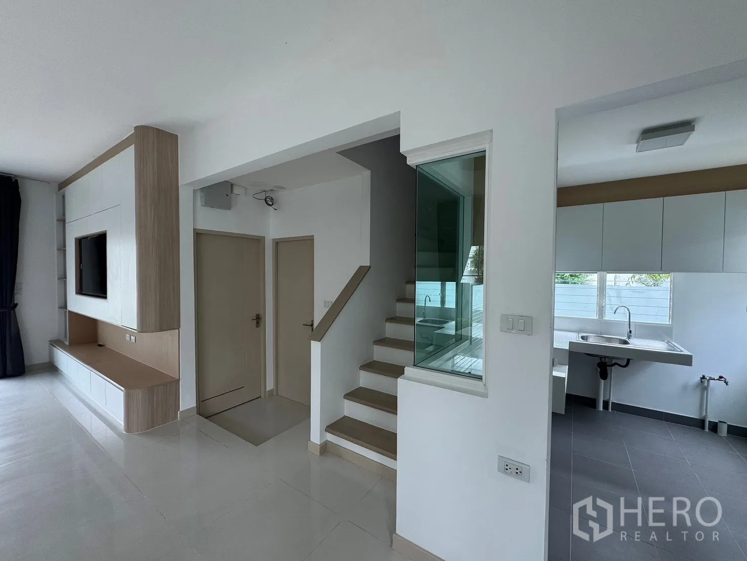 Detached House for rent in Bang Phli, Samut Prakan - Open-plan living room with sectional sofa and a built-in TV wall unit.