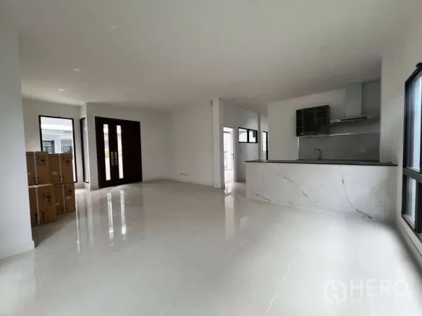 Detached House for rent in Wang Thonglang, Bangkok - Open-plan living and dining area with glossy floors beside a sleek marble-top kitchen and large windows.