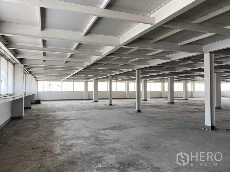 Factory for sale in Khlong Luang, Pathum Thani - Open-plan level with rows of pillars and long strip windows bringing daylight.