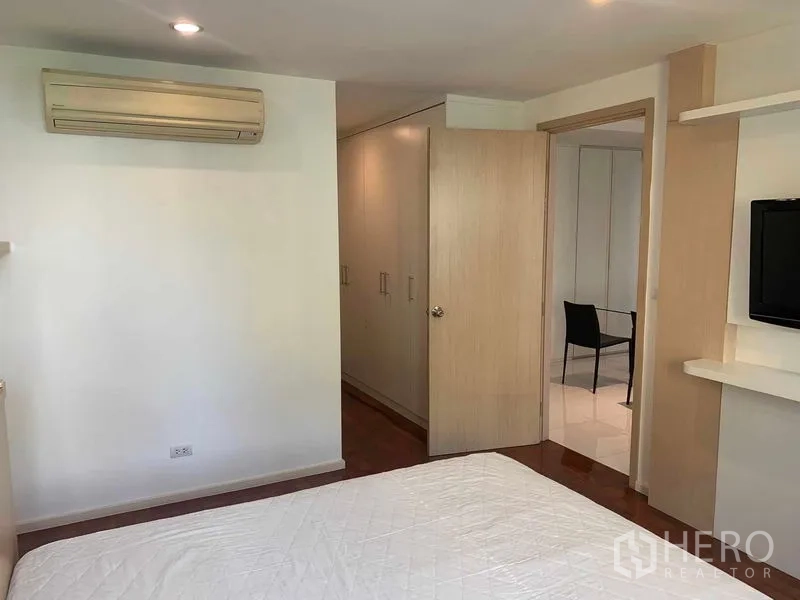 Condominium for rent or sale in Khlong Toei, Bangkok - Bedroom with air conditioner, wardrobes, and TV shelf.