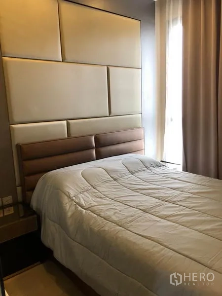 Condominium for rent in Watthana, Bangkok - Cozy bedroom with padded headboard, double bed and soft natural light from a curtained window.