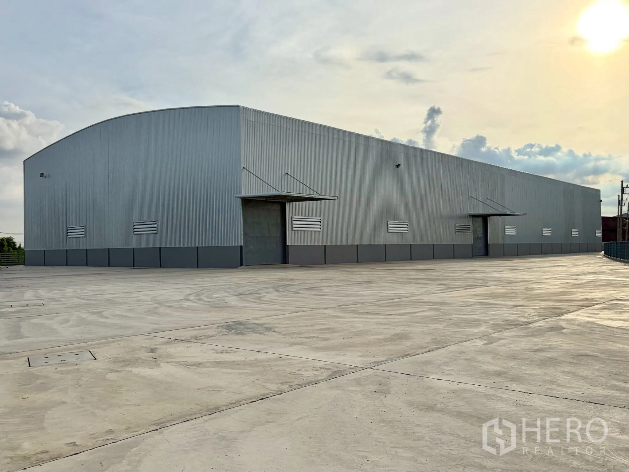 Factory for rent in Uthai, Phra Nakhon Si Ayutthaya - Long side of the metal warehouse with multiple entry doors, vents, and wide maneuvering space.