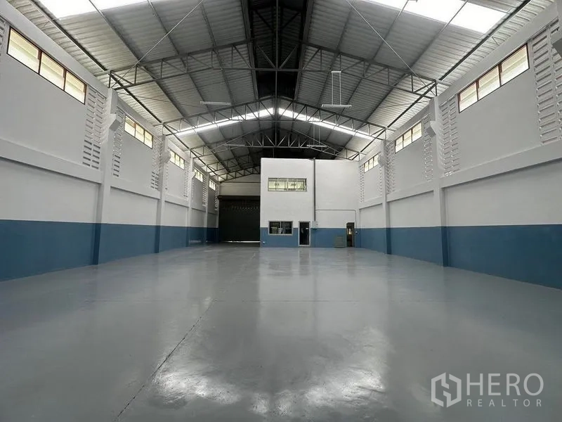 Factory for rent in Pathum Thani - Warehouse interior facing office block and large roller shutter door.