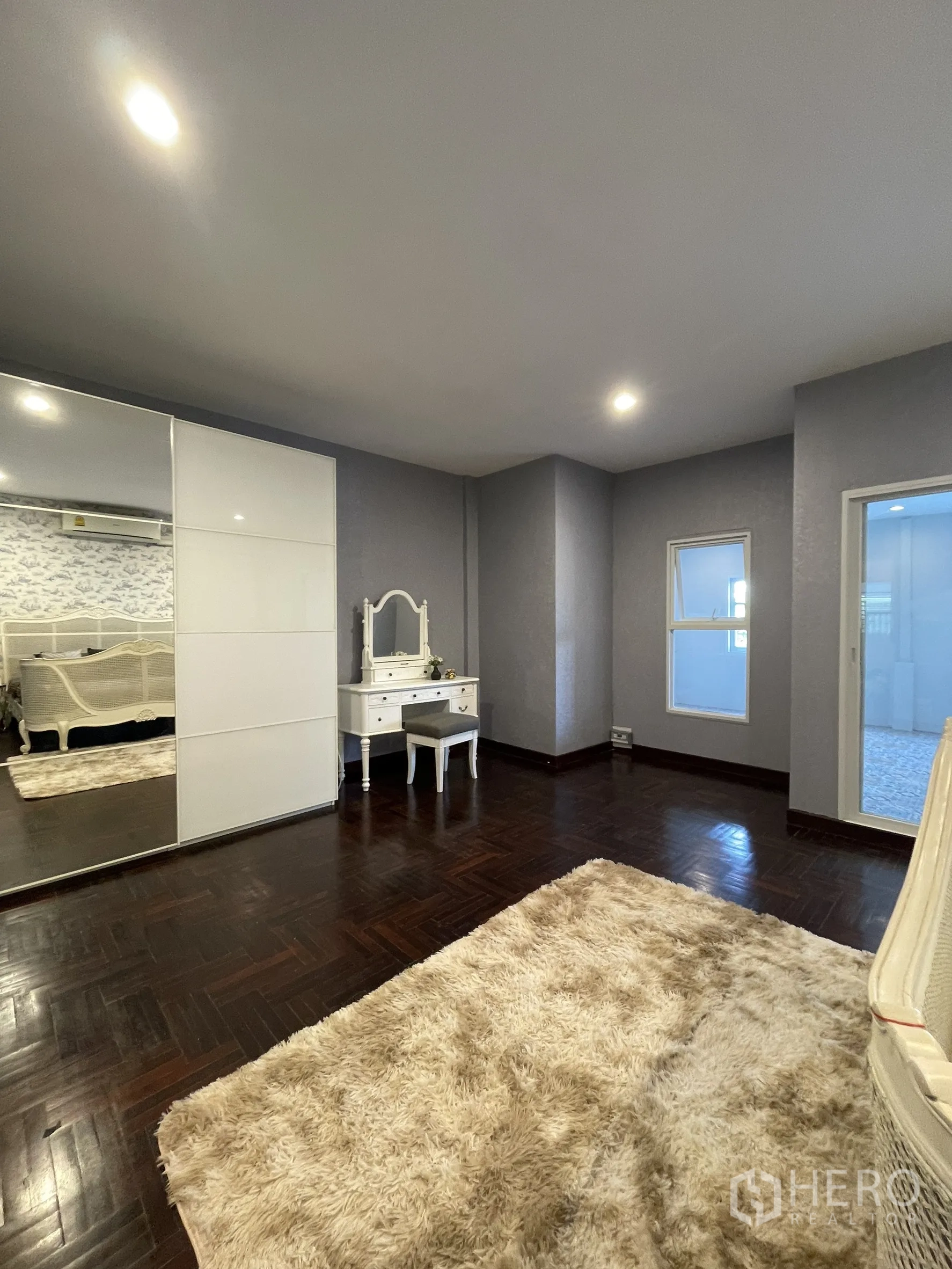 店屋 for rent in Bang Kapi, Bangkok - 卧室一角，镜面衣柜、白色妆台与柔软地毯，地面为深色木纹。