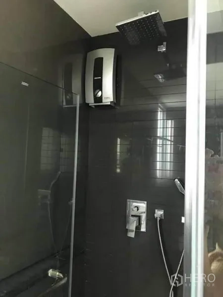 Condominium for rent or sale in Phaya Thai, Bangkok - Bathroom with dark tiles, rainfall shower and water heater inside a glass enclosure.