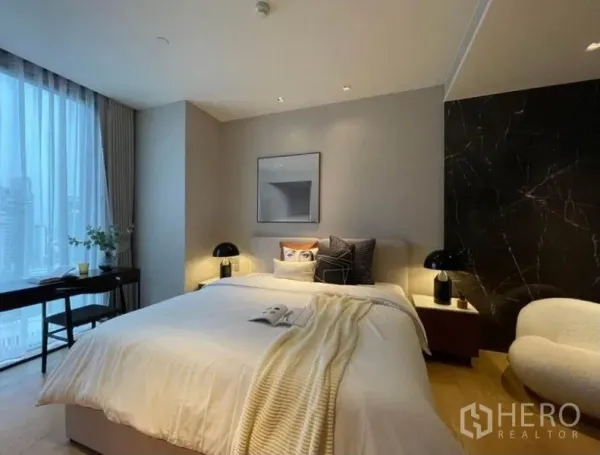 Condominium for rent or sale in Khlong Toei, Bangkok - Primary bedroom with king bed, black marble accent wall, nightstands, and a large window to the city.