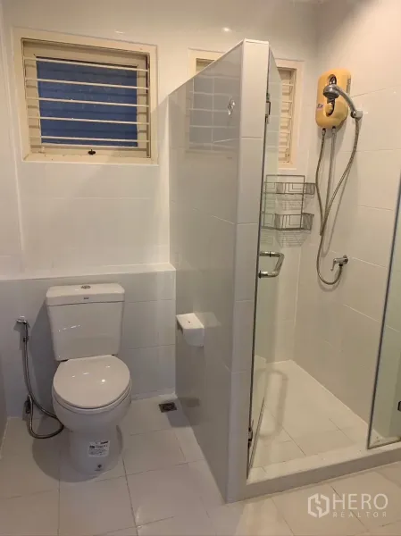 Detached House for rent in Watthana, Bangkok - Bright bathroom with glass shower enclosure and white tiles.