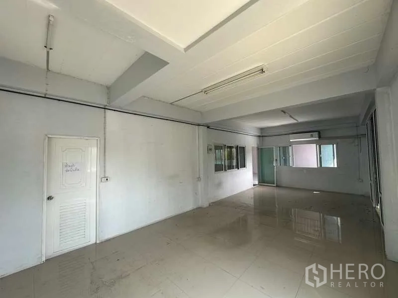 Warehouse for rent in Pathum Thani - Long office room with air-conditioner, tiled flooring and fluorescent lighting.