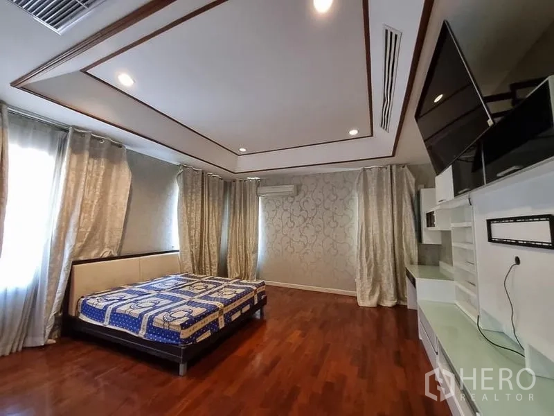 Detached House for rent in Yan Nawa, Bangkok - Large bedroom with hardwood floors, recessed ceiling lights, curtains and built-in shelving.