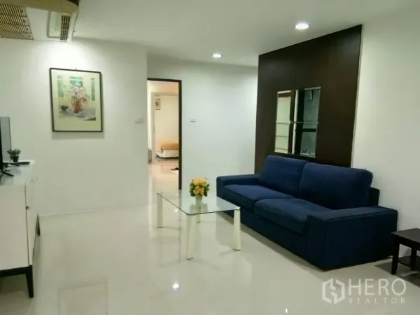 คอนโด ให้เช่าในWatthana, Bangkok - โถงนั่งเล่นกว้าง มองไปทางประตูห้องนอน พร้อมโซฟาสีกรมและโต๊ะกระจก