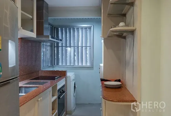 房间 出租在Bang Rak, Bangkok - 狭长型厨房，花岗岩台面，电炉、烤箱、抽油烟机、开放搁架与洗衣机，配百叶窗。