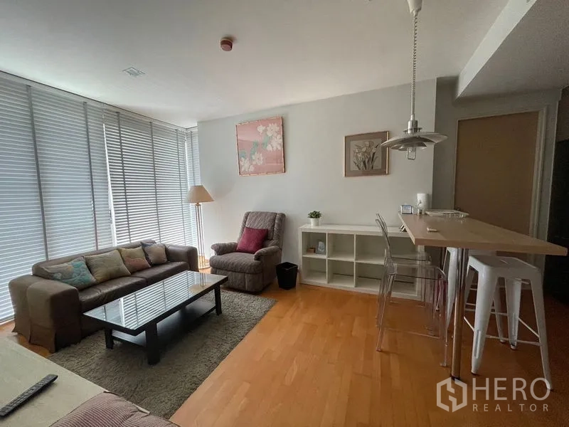 Condominium for sale in Khlong Toei, Bangkok - Open-plan lounge with armchair, pendant light and a breakfast counter.