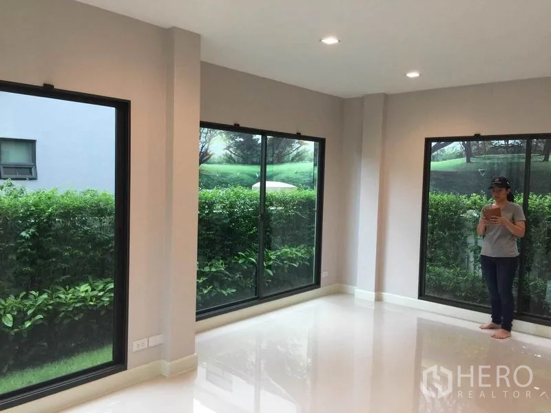 独立式住宅 出售在Pak Kret, Nonthaburi - 采光充足的客厅，大转角落地窗，花园景观