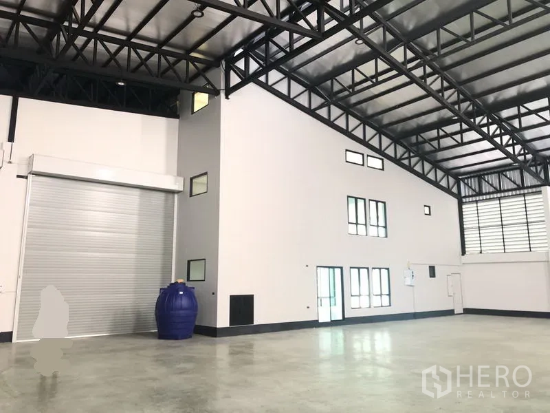 工厂 出售在Pathum Thani - 采光充足的工业大厅，夹层办公室、隔热屋顶与宽卷帘便于卡车出入。