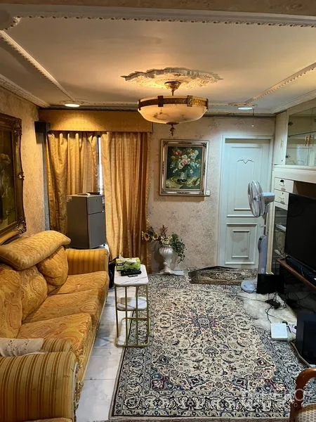 Condominium for sale in Khlong Toei, Bangkok - Cozy sitting room with patterned rug, gold sofa, TV unit and decorative ceiling light.