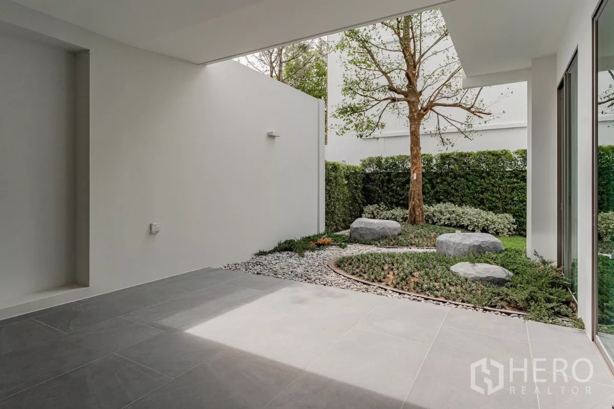 Detached House for rent in Saphan Sung, Bangkok - Covered terrace facing landscaped courtyard with rocks and tree.