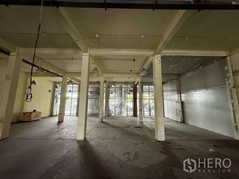 Shophouse for rent - Spacious open-plan ground floor with concrete flooring, columns and full-height windows.