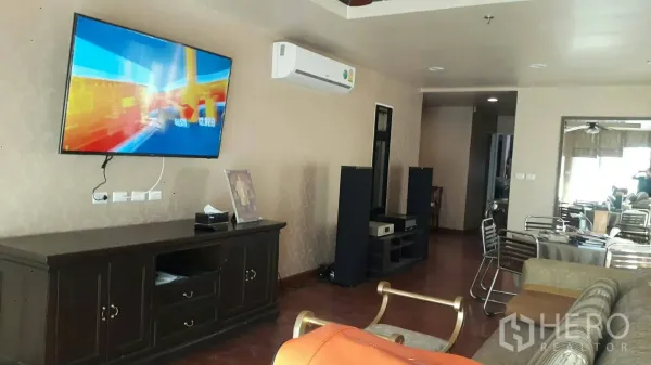 Condominium for rent in Pathum Wan, Bangkok - Open-plan living room with wall-mounted TV, air conditioner and dark wood console.