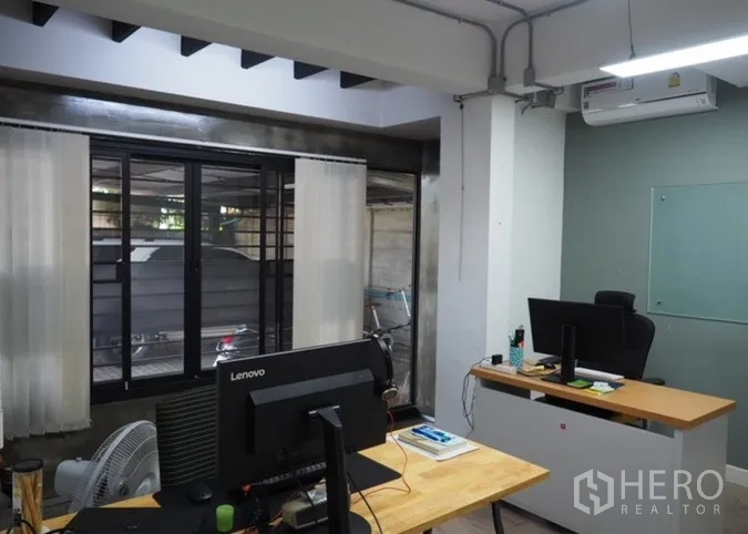 Home Office for rent in Lat Phrao, Bangkok - Air-conditioned office room with desks, large window and exposed ceiling beams.