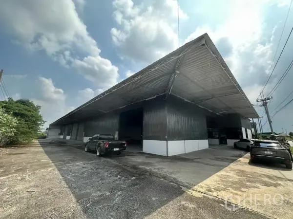 Warehouse for rent in Khlong Luang, Pathum Thani - Metal-clad warehouse exterior with deep covered loading bays and parking in Khlong Luang.