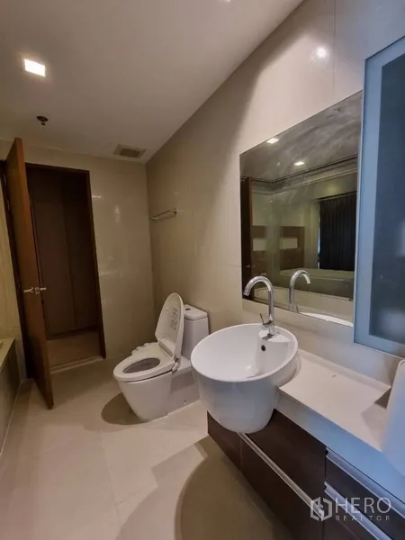 公寓 出租在Watthana, Bangkok - 现代卫浴，设台上盆、大镜面与马桶，紧邻浴缸。