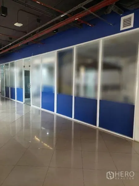 零售空间 出租在Sathon, Bangkok - 沿室内走廊的长排玻璃店面，底部蓝色面板。