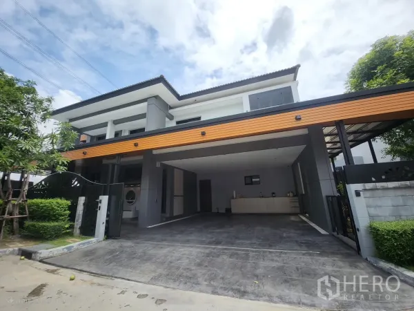独立式住宅 出租在Bang Phli, Samut Prakan - 现代两层独栋住宅的正面外观，带宽阔电动门和覆盖式车棚