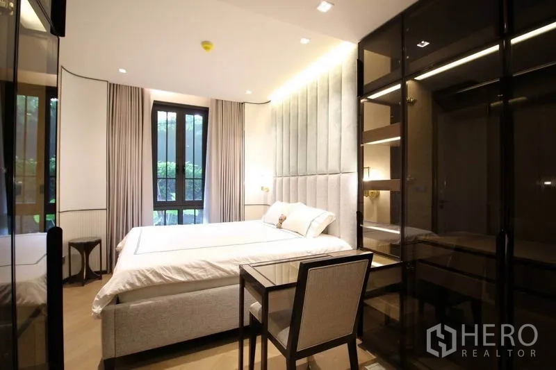 公寓 出租在Watthana, Bangkok - 卧室一角，玻璃衣柜、书写桌与大窗户，窗外绿意盎然。