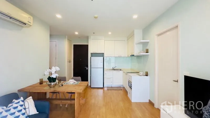 Condominium for rent in Watthana, Bangkok - Open living space showing kitchen, dining table, sofa seating and recessed lighting.