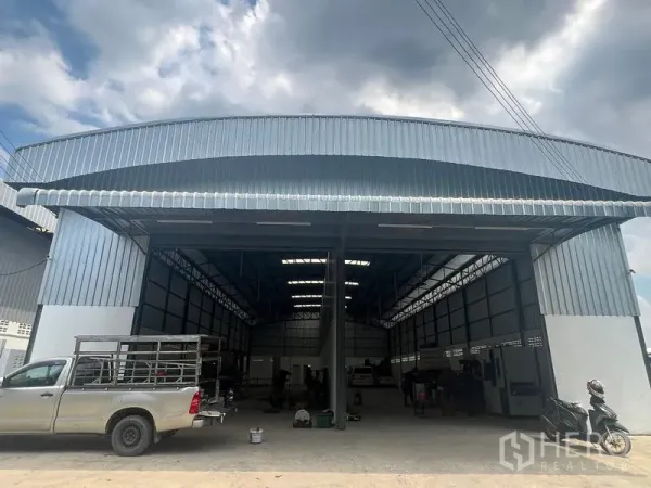 Warehouse for rent in Khlong Sam Wa, Bangkok - Wide facade of the industrial warehouse with metal roof canopy and easy drive-in access for pickups and trucks.